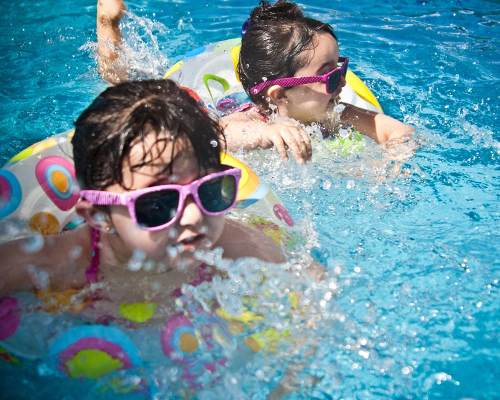 Children playing in a colorful swimming pool with floaties